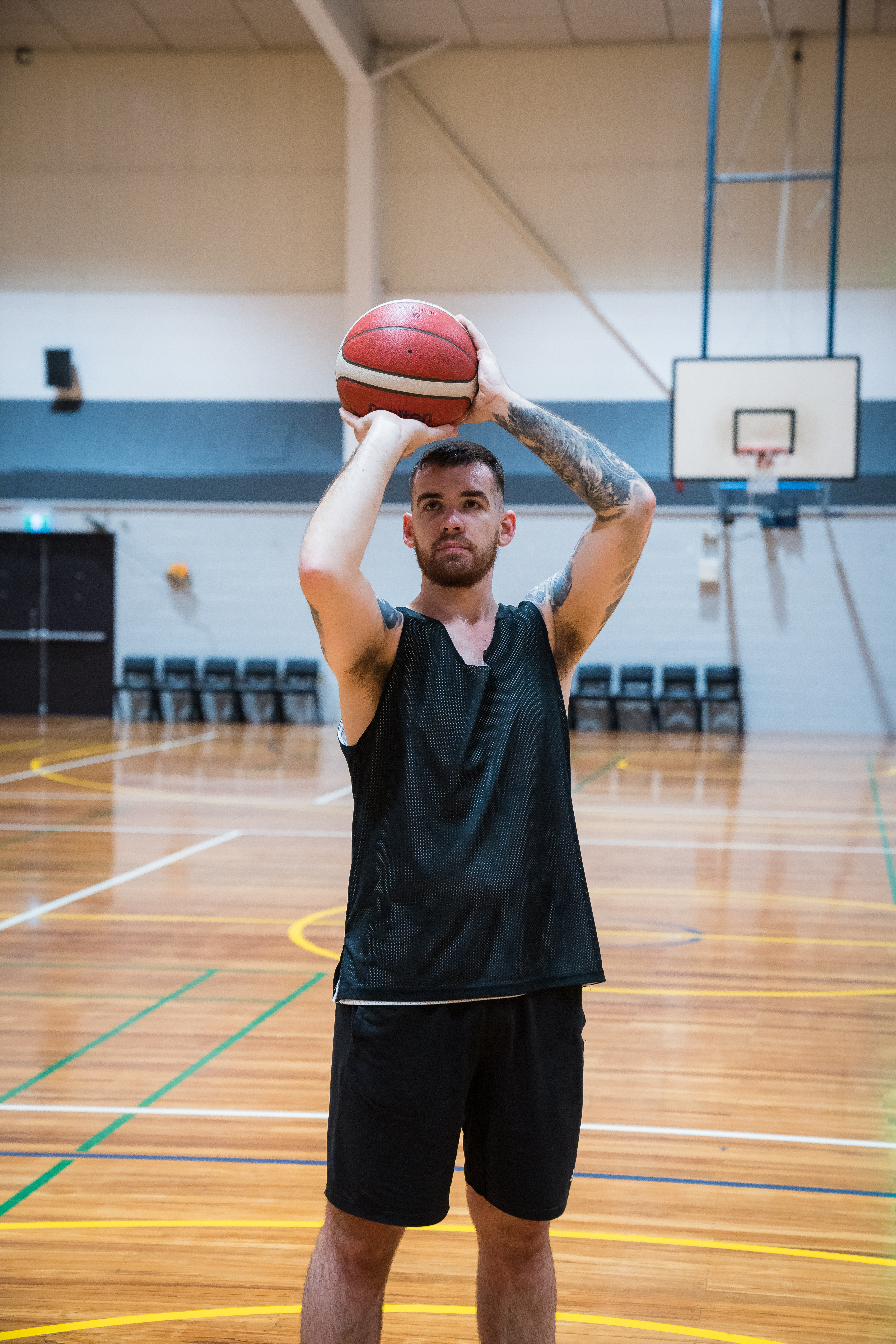 A man holding a basketball above his head about to take a shot in front of a basketball net at Christchurch Recreation and Sport. 