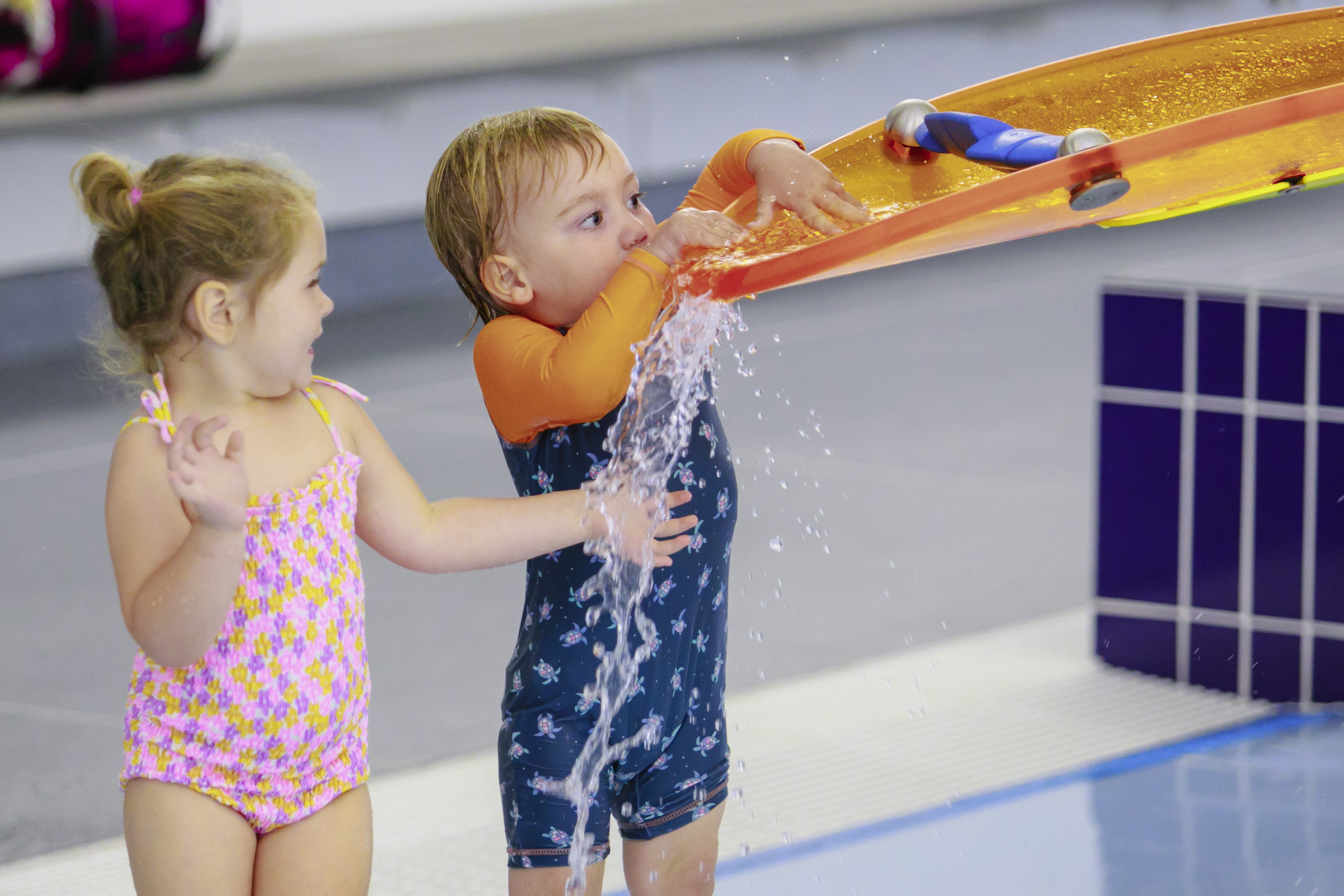 Two children playing in the toddler pool with dump buckets at Matatiki Hornby pool.