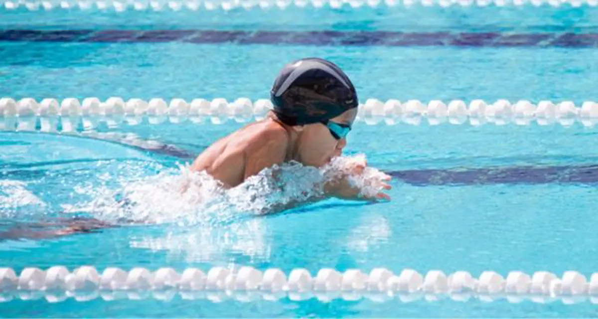 A child in a swim cap and goggles while doing the butterfly stroke at Christchurch Recreation and Sport pool.