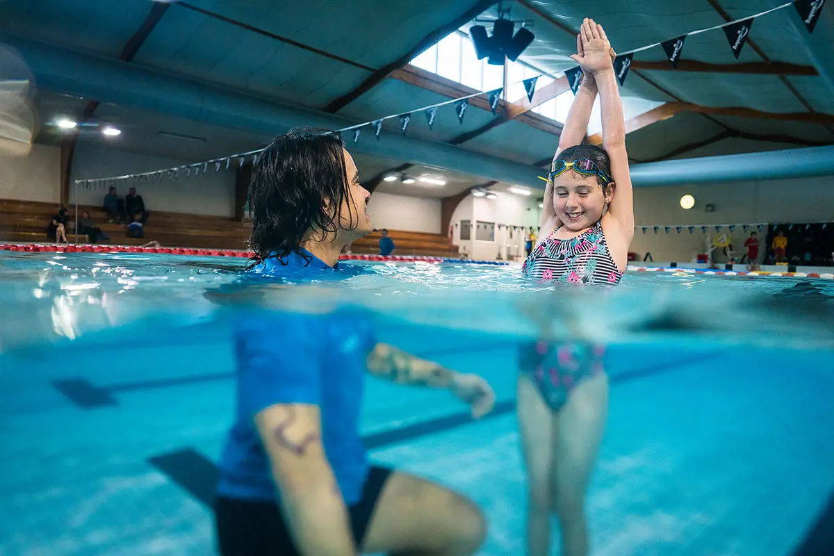 A male swim instructor helping a child practice their diving at Christchurch Recreation and Sport pool.