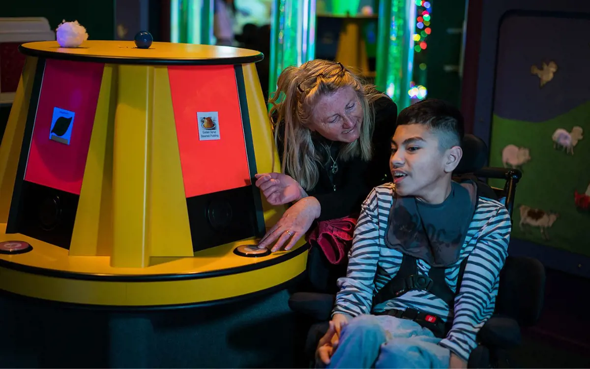 A boy playing with some of the Multi-Sensory Experience games with a smiling woman at Pioneer Recreation and Sport centre.