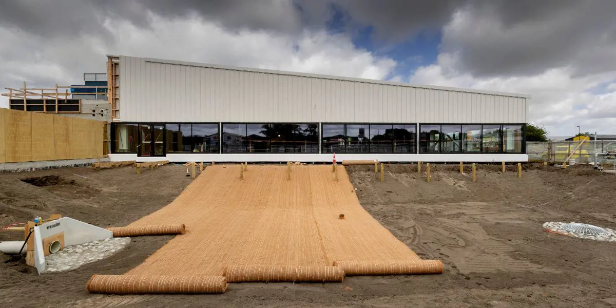 Large sheets of fabric being rolled onto the ground outside of Matatiki Recreation and Sport centre during construction.
