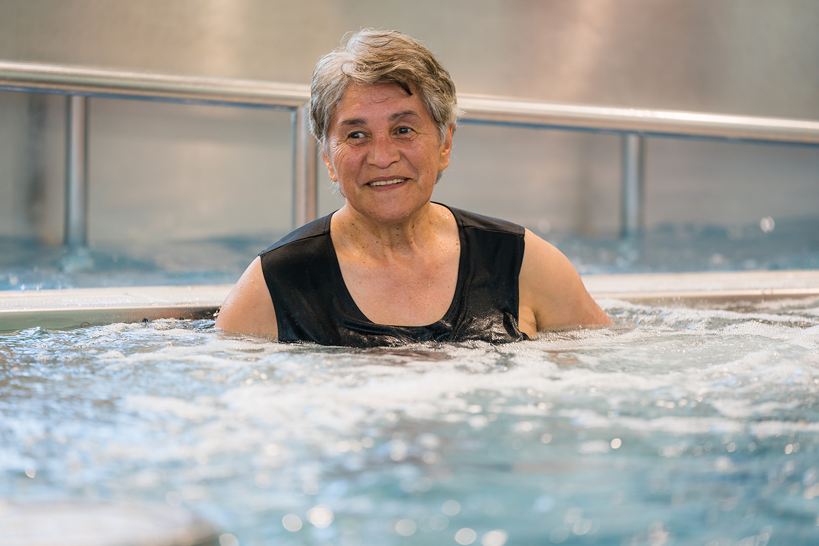 A smiling woman enjoying the spa at Te Pou Toetoe Linwood centre. 