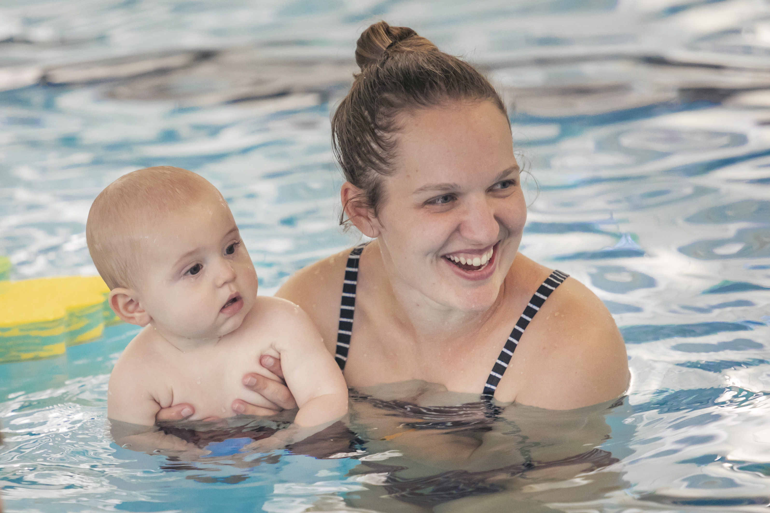 A smiling woman holding onto a toddler at Matatiki Hornby pool. 