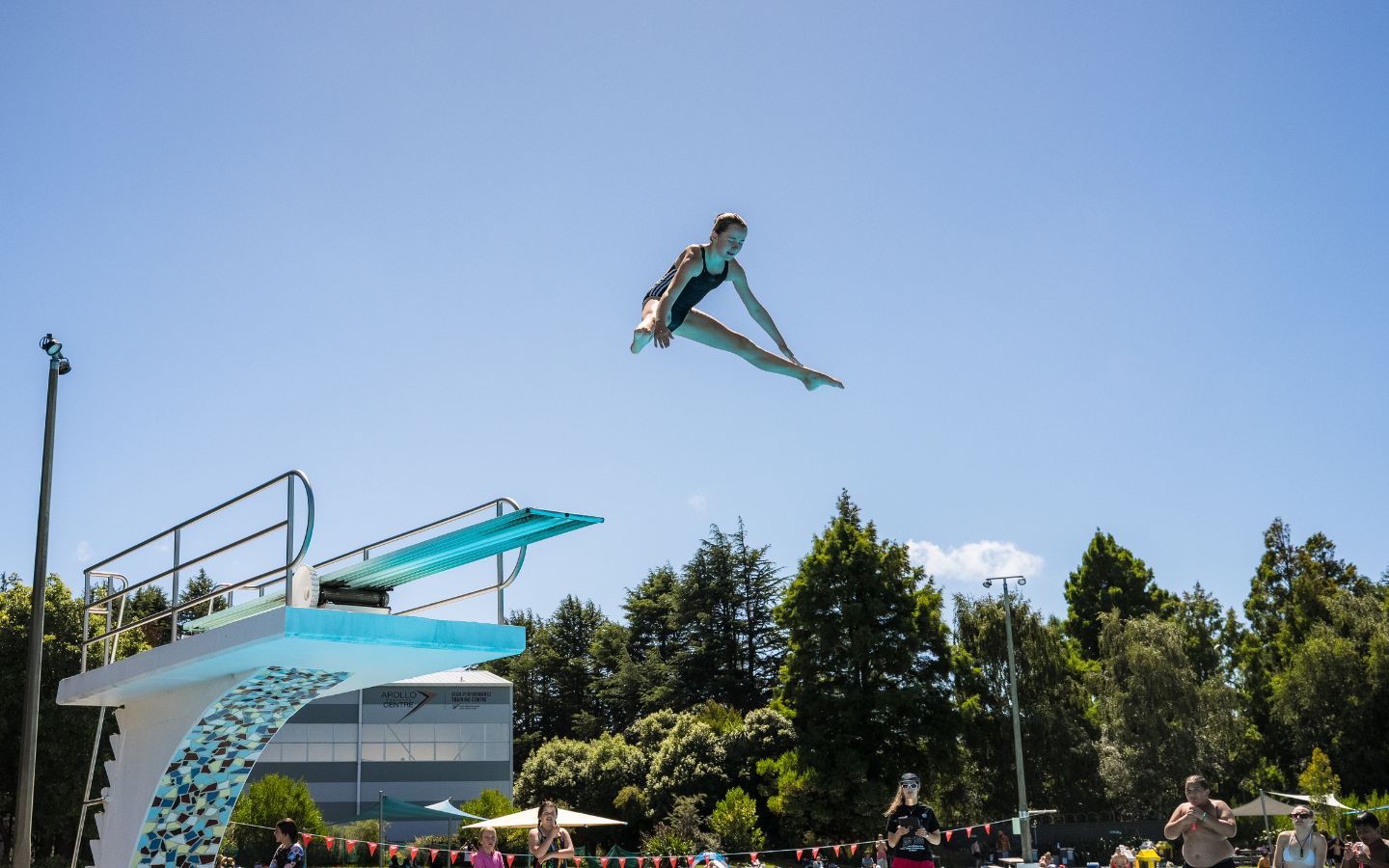 A teenage girl diving off a diving board at Christchurch Recreation and Sport summer pool. 