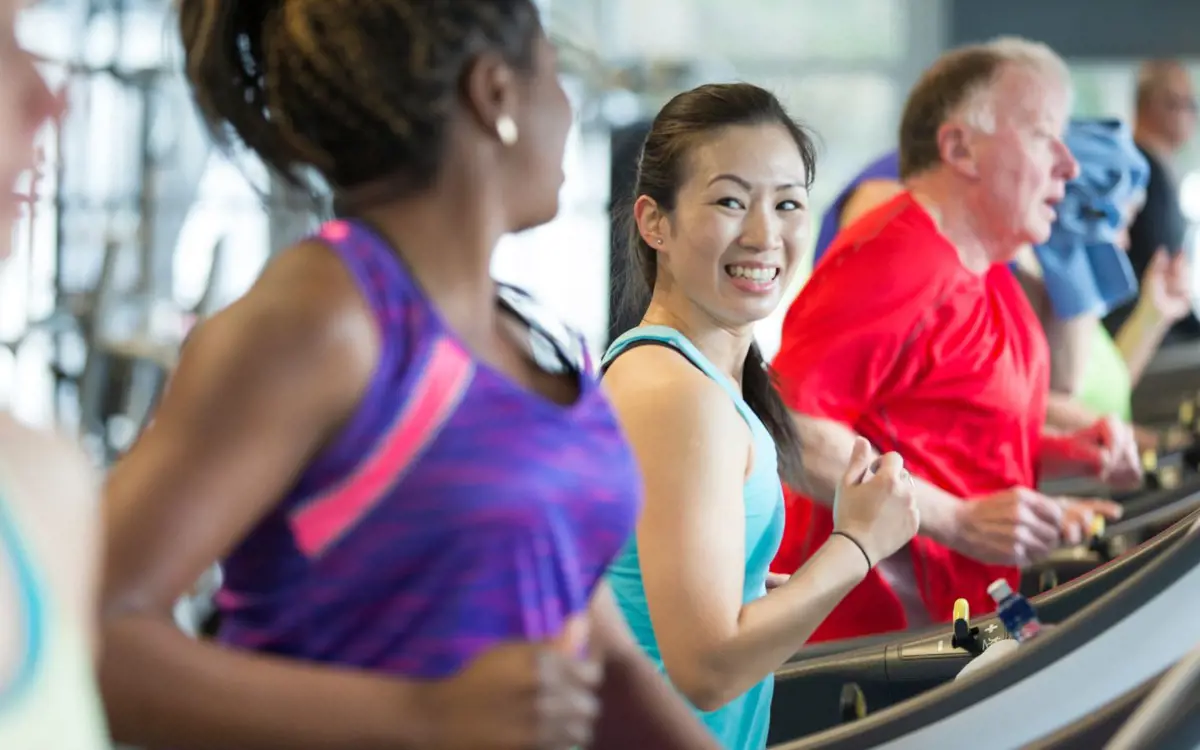 A row of smiling women running on treadmills.