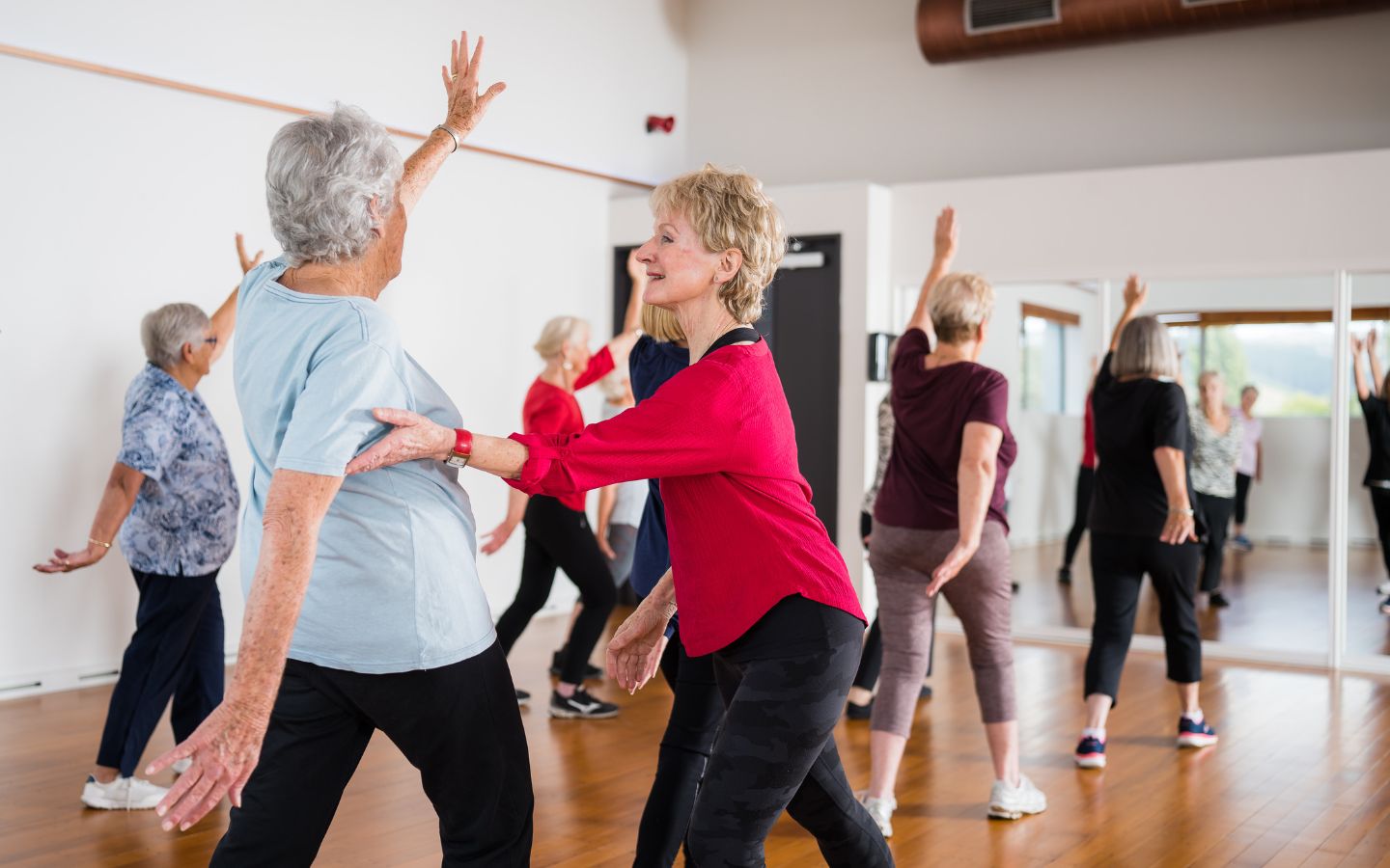 A group of smiling older women stretching during a gentle exercise class at Christchurch Recreation and Sport Centre. 