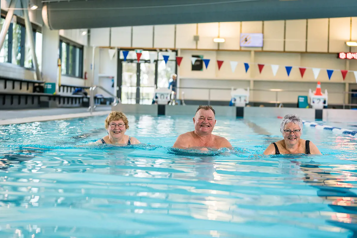 Two older women and an older man smiling standing in the pool at Christchurch Recreation and Sport pool.