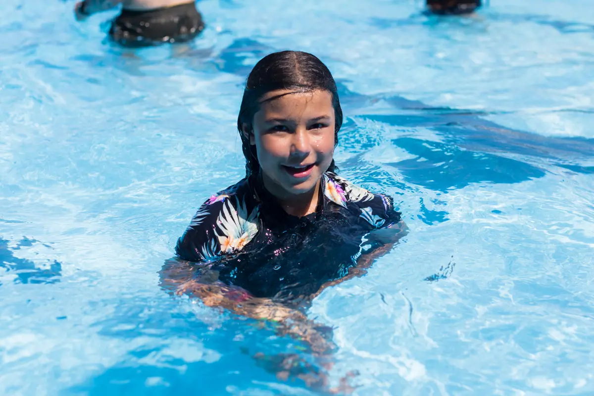 A smiling girl playing at the Waltham Summer pool.