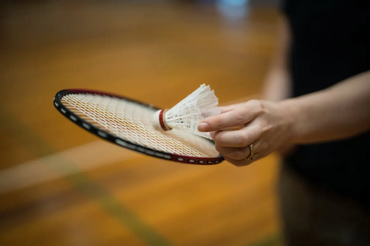 A woman holding a badminton racket and white birdie at Christchurch Recreation and Sport.